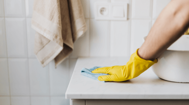 A professional cleaner wiping down a bathroom counter in Austin, TX.